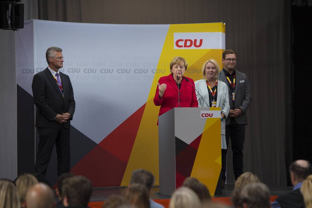 The CDU has launched an investigation into the politician (background, behind Angela Merkel) including money laundering.